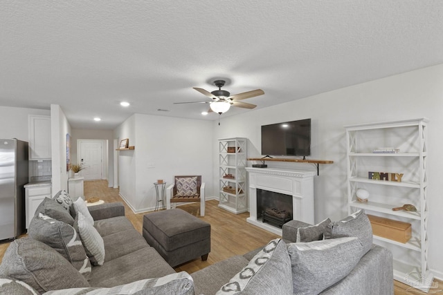 living room featuring a textured ceiling, ceiling fan, and light hardwood / wood-style floors