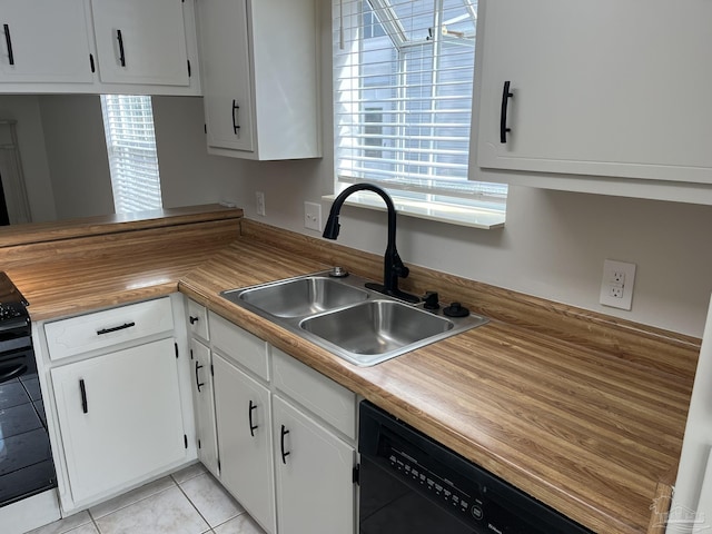 kitchen with light tile patterned flooring, a sink, black appliances, white cabinets, and butcher block counters