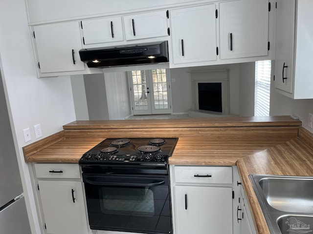 kitchen with white cabinetry, electric range, exhaust hood, and freestanding refrigerator