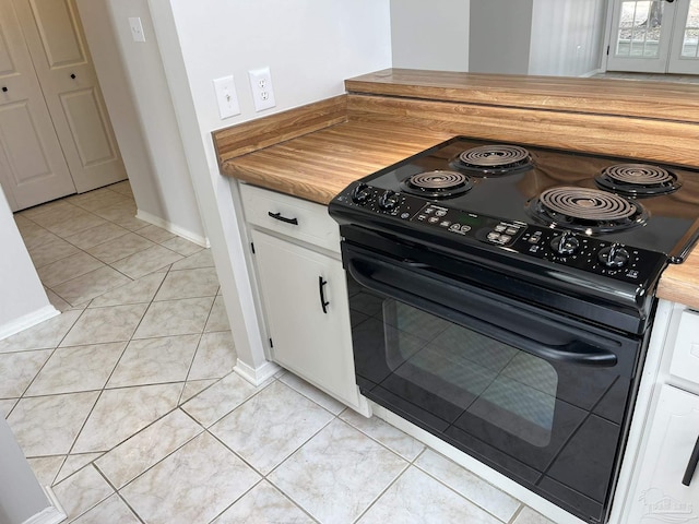 kitchen with black electric range, white cabinets, and light tile patterned floors