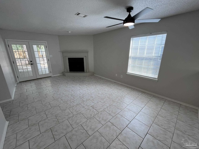 unfurnished living room with visible vents, baseboards, a fireplace with raised hearth, and french doors