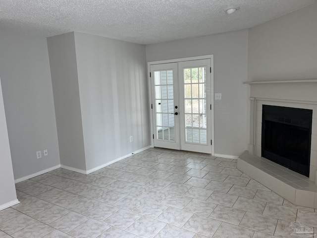 unfurnished living room with a fireplace with raised hearth, a textured ceiling, french doors, light tile patterned floors, and baseboards