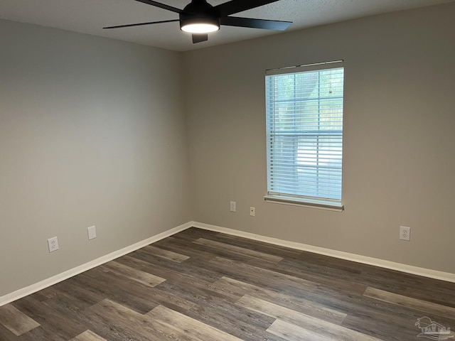 unfurnished room featuring baseboards, dark wood-style flooring, and ceiling fan