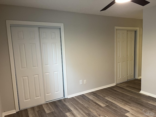 unfurnished bedroom with dark wood-type flooring, baseboards, a closet, and ceiling fan