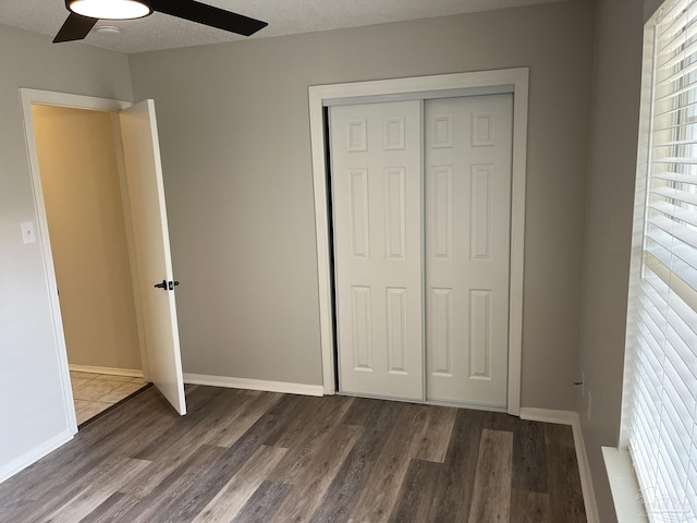 unfurnished bedroom featuring baseboards, wood finished floors, a closet, and a textured ceiling