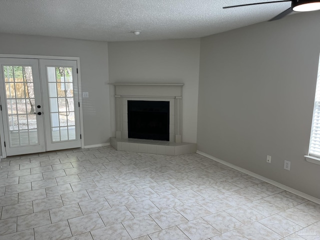 unfurnished living room featuring a textured ceiling, a ceiling fan, baseboards, and a tile fireplace