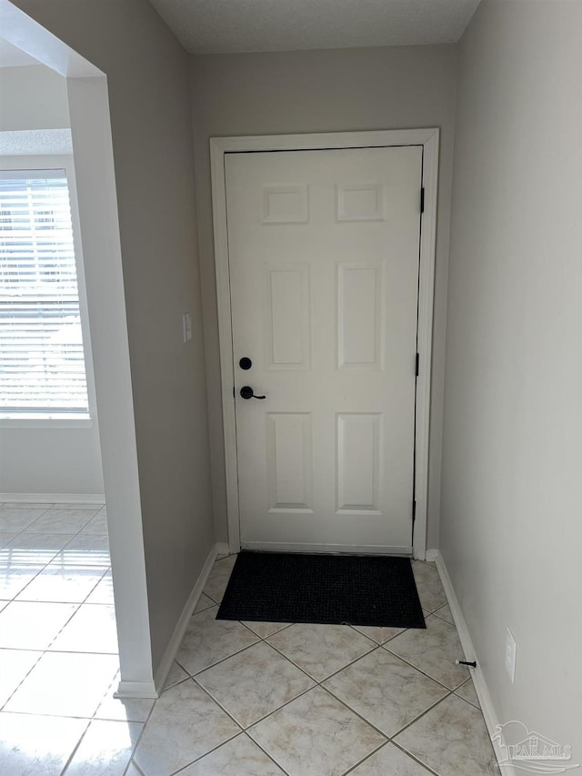 doorway featuring baseboards and light tile patterned flooring