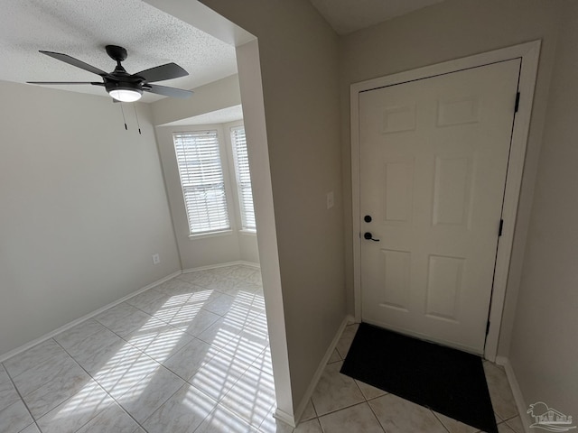 doorway featuring a textured ceiling, baseboards, and a ceiling fan