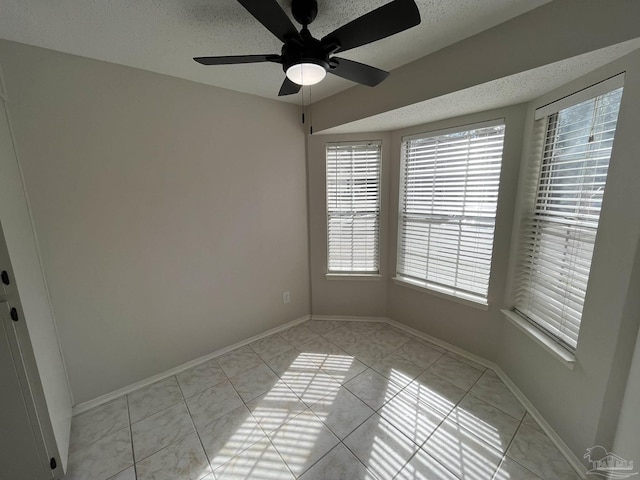 spare room featuring light tile patterned floors, baseboards, and a ceiling fan