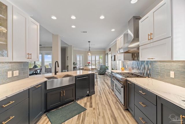 kitchen with high end stainless steel range oven, wall chimney exhaust hood, white cabinetry, and dishwasher