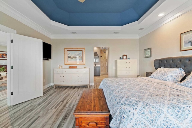 bedroom featuring a tray ceiling, arched walkways, visible vents, connected bathroom, and wood finished floors