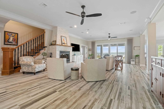 living area with a large fireplace, a healthy amount of sunlight, visible vents, and light wood finished floors