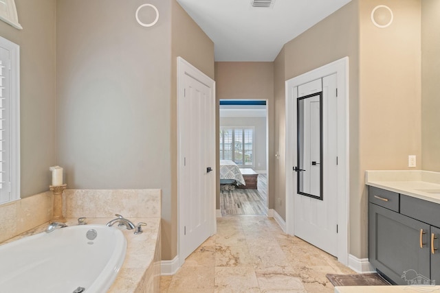 ensuite bathroom with visible vents, vanity, ensuite bath, baseboards, and a bath