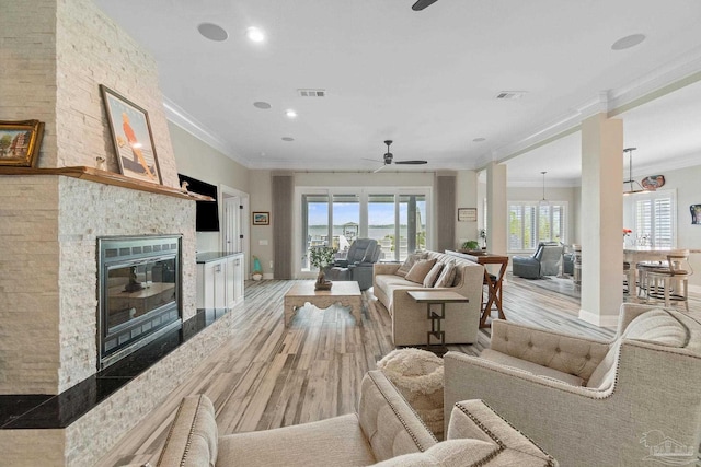 living room with a large fireplace, visible vents, and light wood-style flooring