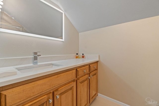 bathroom featuring baseboards, vaulted ceiling, and vanity