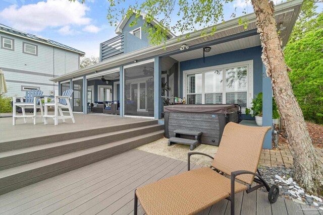 wooden terrace with ceiling fan, a sunroom, and a hot tub