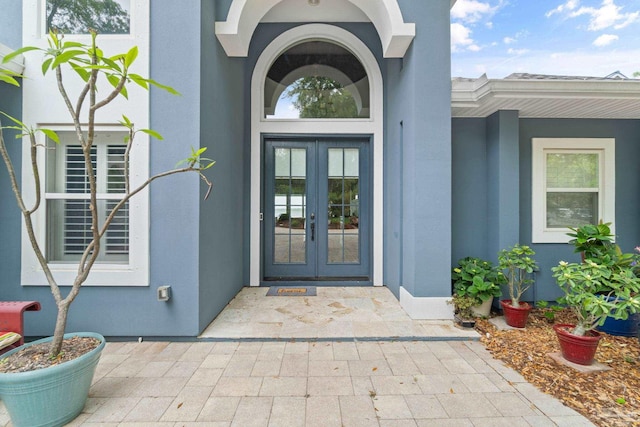 view of exterior entry featuring stucco siding and french doors