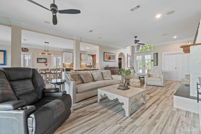 living area featuring visible vents, arched walkways, a ceiling fan, french doors, and light wood-style floors