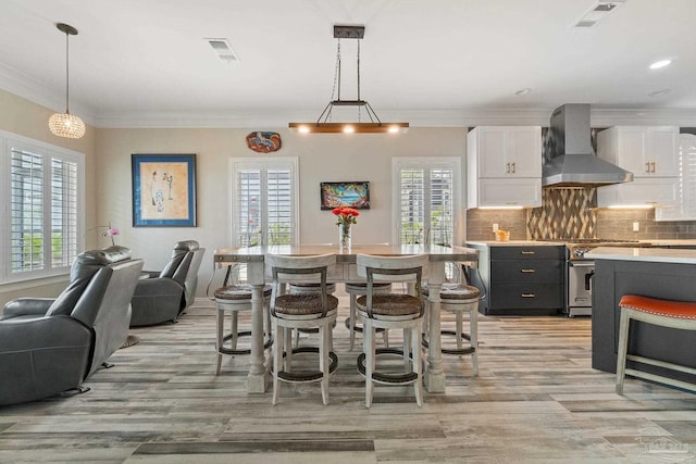 kitchen featuring visible vents, decorative backsplash, white cabinetry, high end stove, and wall chimney exhaust hood