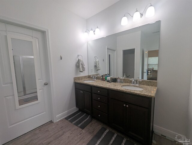 bathroom featuring double vanity, a sink, baseboards, and wood finished floors