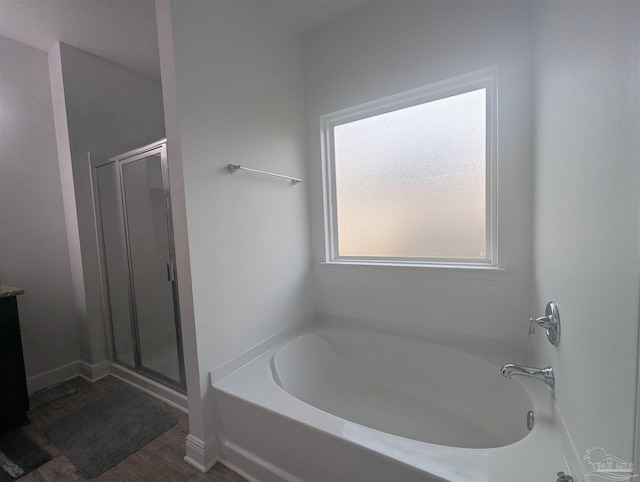 bathroom with a garden tub, a shower stall, and wood finished floors