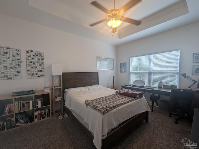 carpeted bedroom featuring a tray ceiling and a ceiling fan