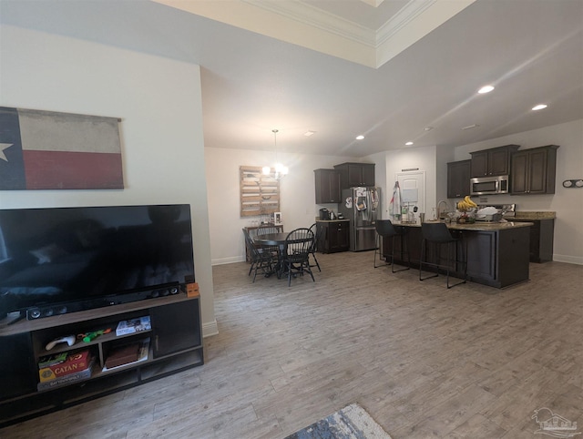 living room featuring light wood-style flooring, ornamental molding, baseboards, and recessed lighting