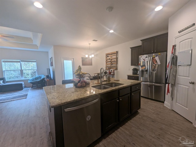 kitchen with stainless steel appliances, light stone counters, a sink, and dark wood finished floors