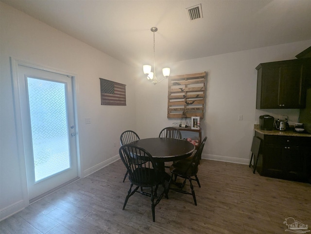 dining room featuring baseboards, visible vents, a chandelier, and wood finished floors