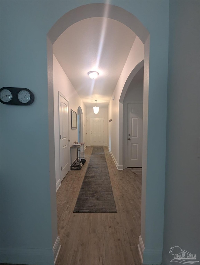 corridor featuring wood finished floors and baseboards