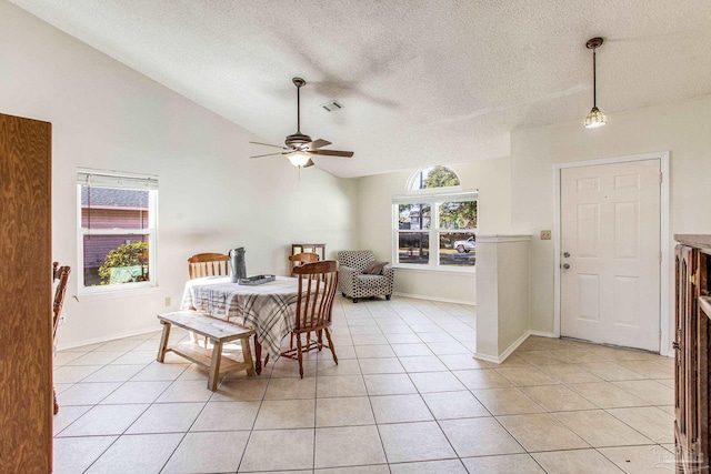 tiled dining space featuring vaulted ceiling, ceiling fan, and a textured ceiling