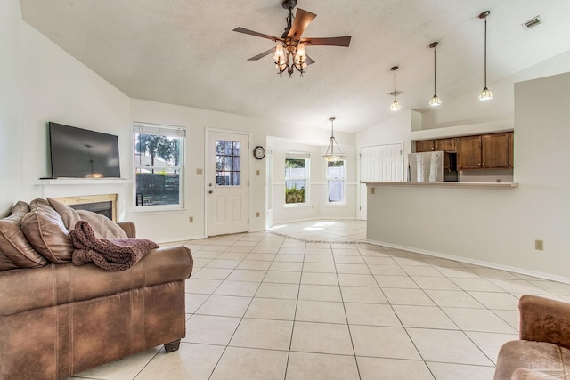 tiled living room with lofted ceiling, ceiling fan, a fireplace, and plenty of natural light