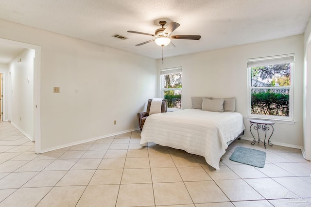 tiled bedroom with ceiling fan, multiple windows, and a textured ceiling