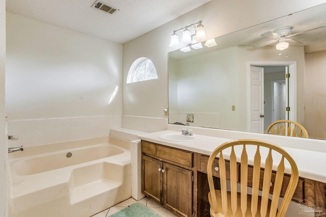 bathroom featuring ceiling fan, vanity, tile patterned flooring, a tub to relax in, and a textured ceiling