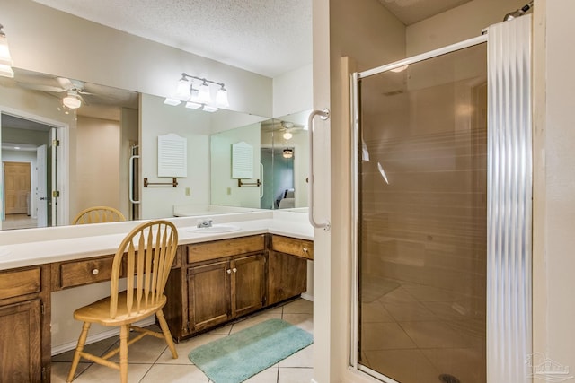 bathroom featuring ceiling fan, vanity, tile patterned floors, a textured ceiling, and a shower with door