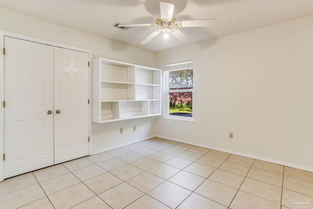 unfurnished bedroom with ceiling fan, light tile patterned floors, and a closet