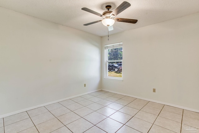 empty room featuring ceiling fan, light tile patterned floors, and a textured ceiling