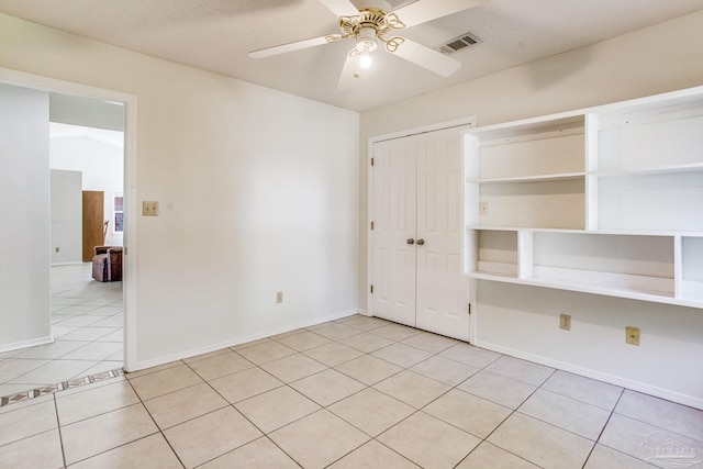 unfurnished bedroom with a textured ceiling, ceiling fan, light tile patterned floors, and a closet