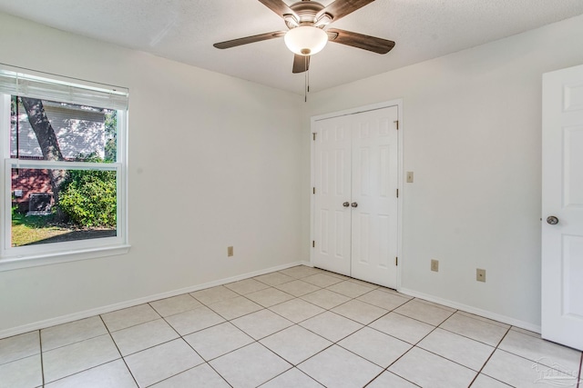 unfurnished bedroom featuring ceiling fan, a closet, multiple windows, and a textured ceiling