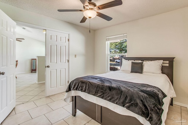 bedroom with a textured ceiling, ceiling fan, light tile patterned flooring, and vaulted ceiling