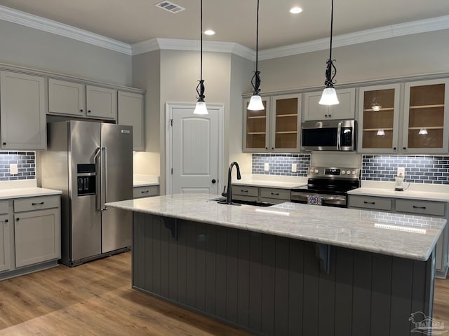 kitchen with light stone countertops, appliances with stainless steel finishes, light wood-type flooring, gray cabinetry, and sink