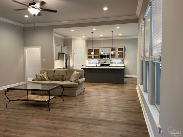 living room featuring ceiling fan, sink, dark hardwood / wood-style floors, and ornamental molding