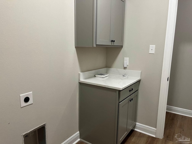 clothes washing area with cabinets, dark hardwood / wood-style floors, and electric dryer hookup