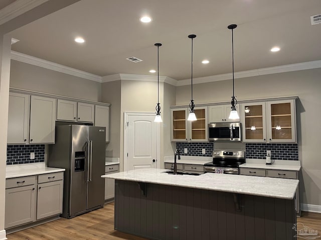 kitchen featuring hanging light fixtures, sink, appliances with stainless steel finishes, and light hardwood / wood-style flooring