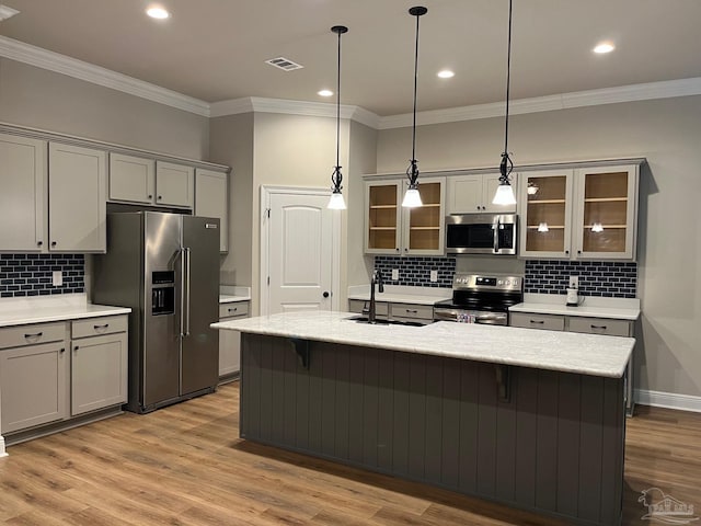 kitchen with sink, light wood-type flooring, stainless steel appliances, and hanging light fixtures