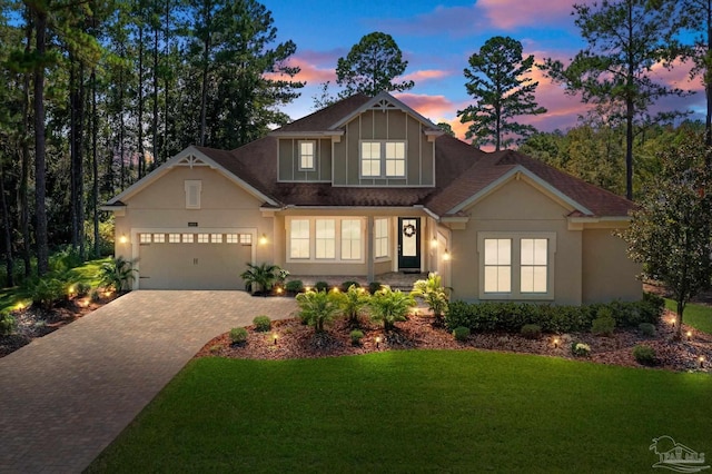 view of front of property with decorative driveway, a front yard, an attached garage, and stucco siding
