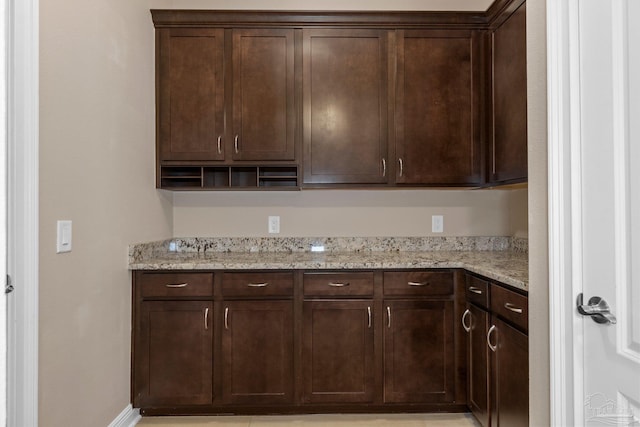 kitchen featuring light stone countertops and dark brown cabinetry