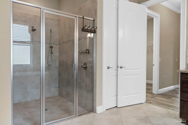 bathroom with tile patterned flooring, a shower with door, ornamental molding, and vanity