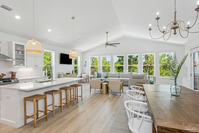 kitchen with white cabinetry, decorative light fixtures, light hardwood / wood-style floors, and sink