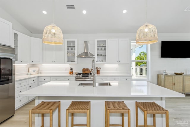 kitchen featuring stainless steel appliances, a kitchen breakfast bar, and wall chimney range hood